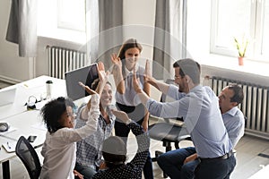 Diverse young colleagues give high five engaged in teambuilding