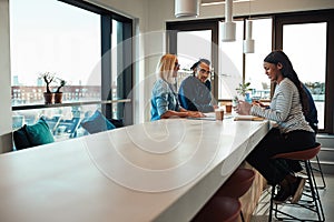 Diverse young colleagues meeting around a table in an office