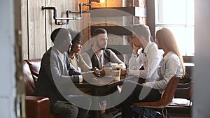 Diverse young friends talking drinking coffee in cozy loft coffeehouse