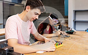 Diverse young high school students learning in science robotics electronic class