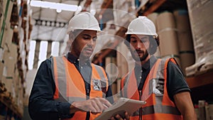 Diverse young male workers discussing and using digital tablet while supervising production at distribution warehouse