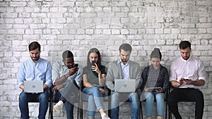 Diverse young people with gadgets, waiting for job interview.