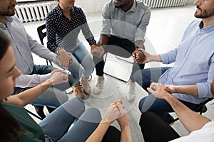 Diverse young people hold hands participate in group therapy