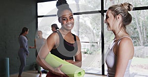 Diverse young women talking and looking at camera cheerfully while standing in studio