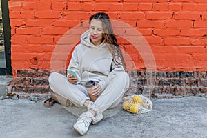 Diversity adult woman, sits on street and drinks coffee from a thermo mug, looks into phone camera and takes selfie.Zero waste