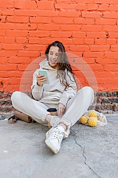 Diversity adult woman, sits on street and drinks coffee from a thermo mug, looks into phone camera and takes selfie.Zero waste