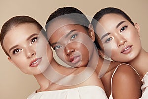 Diversity. Beauty Portrait Of Different Ethnicity Women. Multi-Ethnic Models Standing Together Against Beige Background.