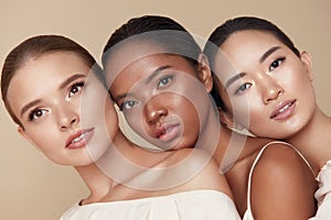 Diversity. Beauty Portrait Of Different Ethnicity Women. Multi-Ethnic Models Standing Together Against Beige Background. photo
