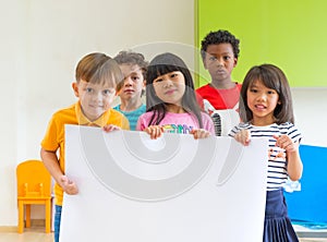 Diversity children holding blank poster in classroom at kindergarten preschool,Multiethnic Group with sign board,mock up for