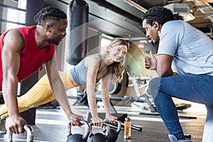 Diversity couple doing push-ups in gym with coach