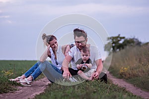 Diversity family of three enjoys peaceful moment together, seated along country trail