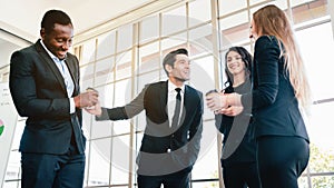 Diversity group of businesspeople strictly dressed in the suits standing meeting by office window.