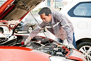 Diversity mechanic teamwork, a Japanese engineer wearing blue uniforms. A man inspects problems of the car engine inside opened