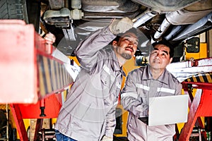 Diversity mechanic teamwork, a Thai and Japanese man in yellow and blue uniforms. A Thai man inspects the car bottom.