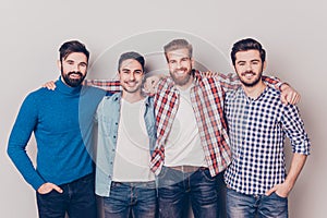Diversity of men. Four cheerful young guys are standing and embracing, smiling, on pure background in casual outfit and jeans