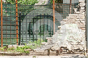 Diversity of old brick wall damaged by age and new modern metal fence of the garden