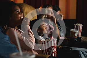 Diversity people children and young people having fun watching movie and eating popcorn in cinema theater