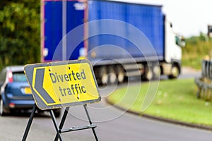 Diverted traffic sign on UK motorway junction with lorry truck in background in England