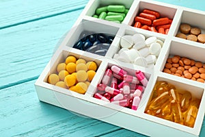 Divided box with different pills on wooden background