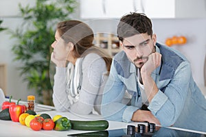 Divided couple with arms crossed in kitchen