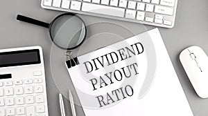 DIVIDEND PAYOUT RATIO written on paper with office tools and keyboard on the grey background