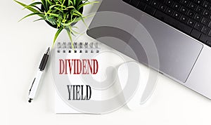 DIVIDEND YIELD text on notebook with laptop, mouse and pen