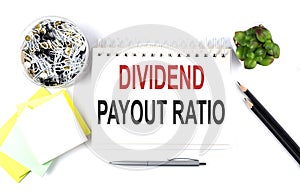 DIVIDENT PAYOUT RATIO text on notebook with office supplies on white background