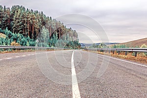 The dividing strip on the asphalt road passing through the mountain forest