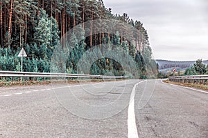The dividing strip on the asphalt road passing through the mountain forest