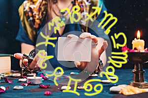 Divination and astrology. The fortune teller shows an empty white tarot card. Zodiac circle.Mock up. Cartomancy and fortune photo