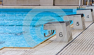 Diving block stands with numbers in outdoor swimming pool on rainy day