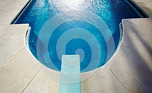 Diving board view from above and blue water of swimming pool