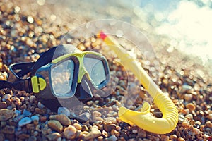 Diving concept - black mask and snorkel on Pebble beach