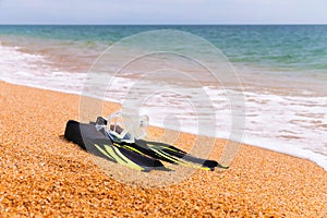 diving goggles, snorkel and fins on the beach with yellow sand. close-up of snorkeling equipment, against the backdrop