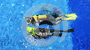 Diving instructor and students. Instructor teaches students to dive in the swimming pool. Scuba diving school concept