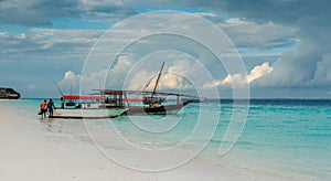 Diving instructors putting equipment in touristic boat on Zanzibar shore