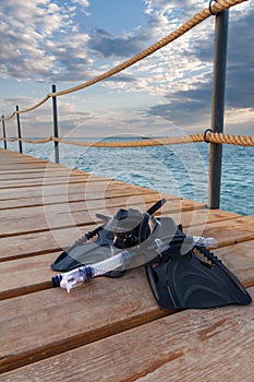 Diving mask, fins and snorkel for professionals on wooden pier.