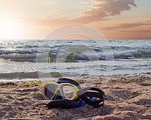 Diving mask on a sandy beach against the sea