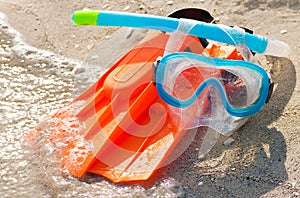 Diving mask, snorkel and fins on a sandy beach