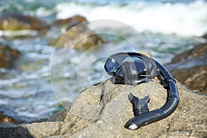 Diving mask and snorkel tube on a rocky seashore