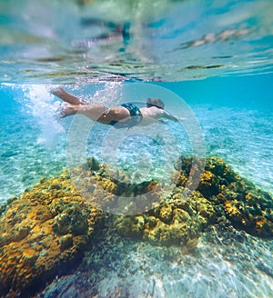 Diving teenage boy snorkeling over the coral reefs underwater photo in the clean turquoise lagoon on Le Morne beach. Mauritius