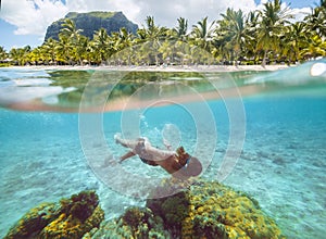 Diving teenage boy snorkeling over the coral reefs underwater photo in the clean turquoise lagoon on Le Morne palm trees beach