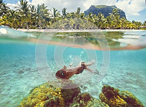 Diving teenage boy snorkeling over the coral reefs underwater photo in the clean turquoise lagoon on Le Morne palm trees beach