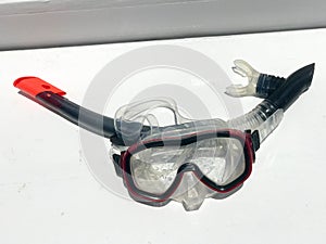 Diving transparent wet mask for swimming under water with a black breathing tube under the water on a white background