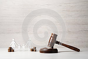 Divorce concept. Gavel, wedding rings, coins and paper cutout of family on white wooden table, space for text