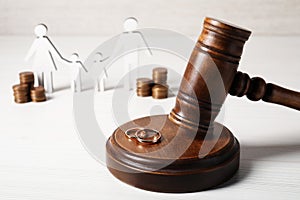 Divorce concept. Gavel and wedding rings on white wooden table, space for text