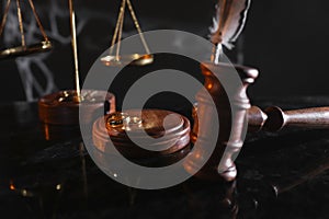 Divorce and law concept. Judge gavel and gold rings on a glossy table