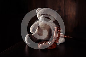 Divorce and separation concept. Wooden gavel, rings and teddy bear as symbol of child. Family law