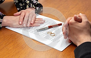 Divorce signature, marriage dissolution document. Wedding ring and agreement on lawyer office table photo