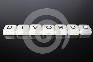 Divorce text word title caption label cover backdrop background. Alphabet letter toy blocks on black reflective background. White
